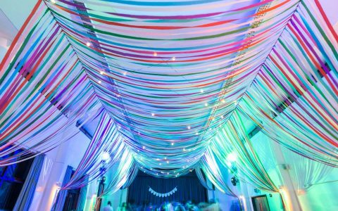 colourful-ribbon-canopy-wedding-reception-town-village-hall-celebration-beautiful-oculux-lighting-evening