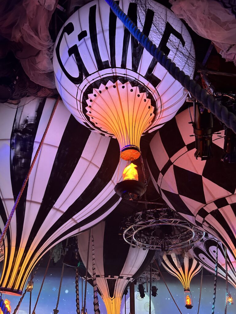 A hot air balloon with an illuminated replica hot air burner beneath, designed as a theatrical piece for The Grand Exhibition immersive theatre project.